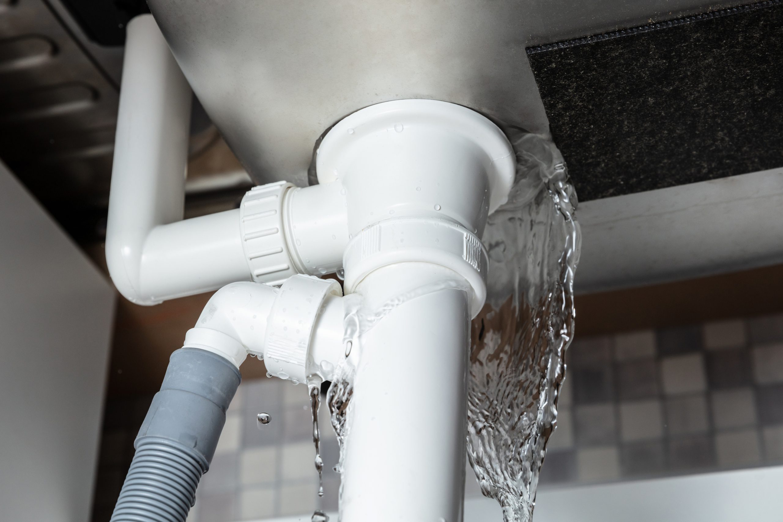 Water leaking from the pipe beneath a household sink
