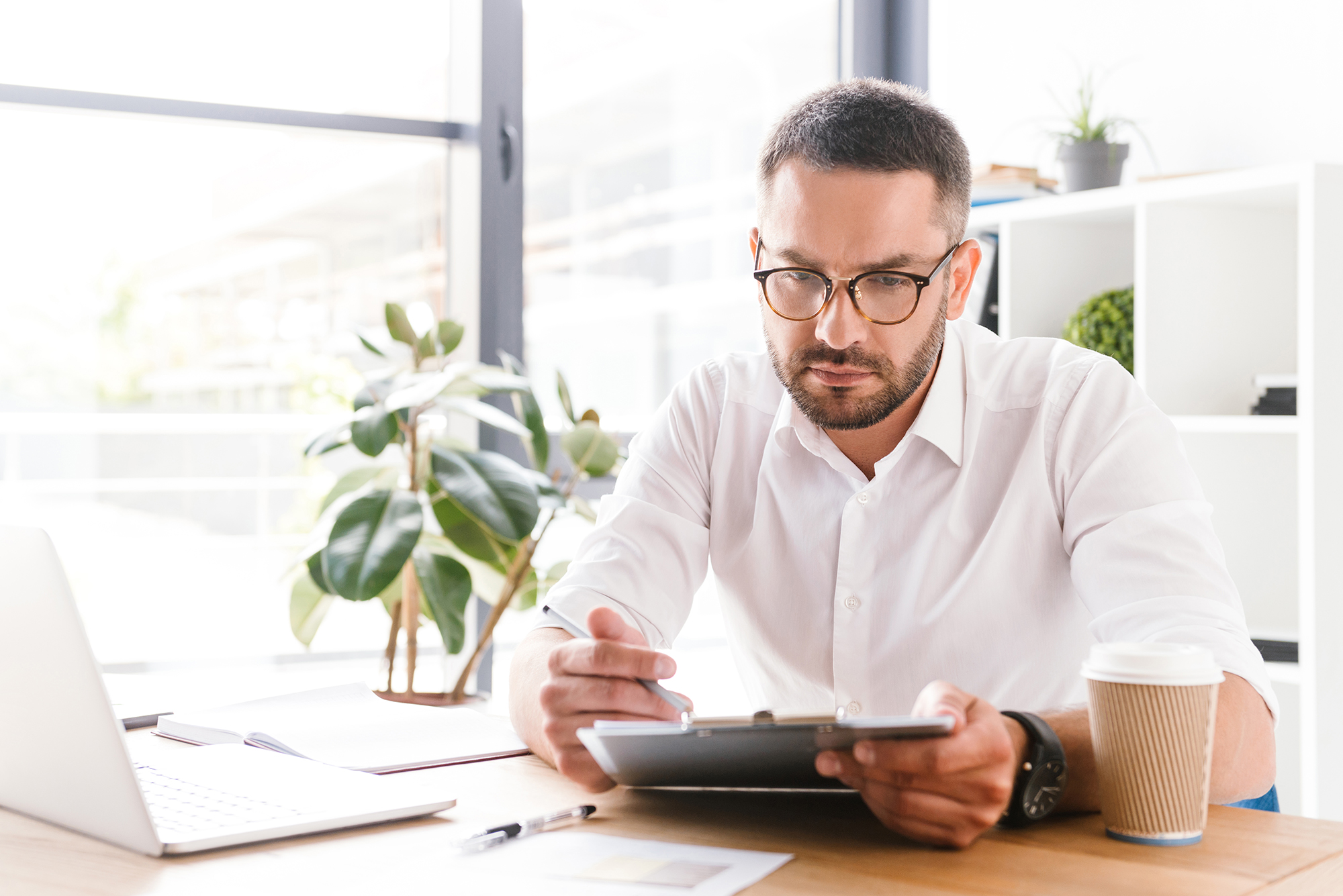 Man reviewing documents on a clipboard in an office